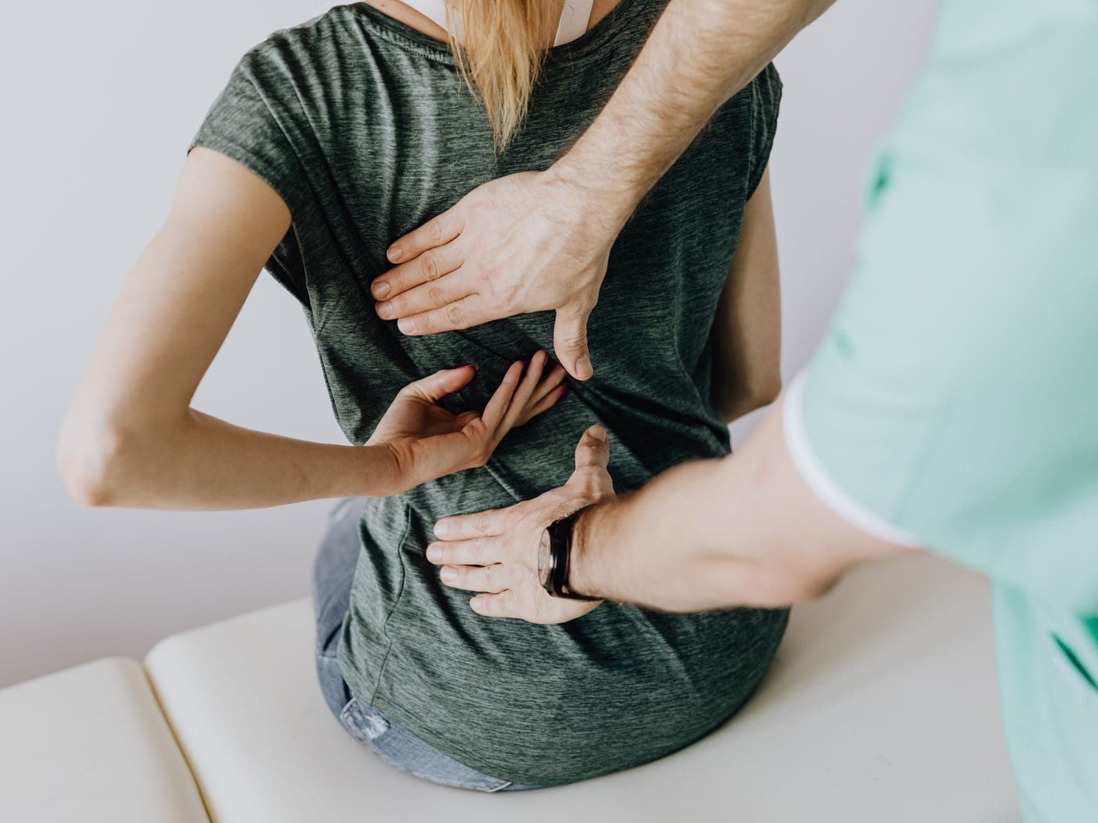 A patient pointing to the painful spot on her lower back during an examination
