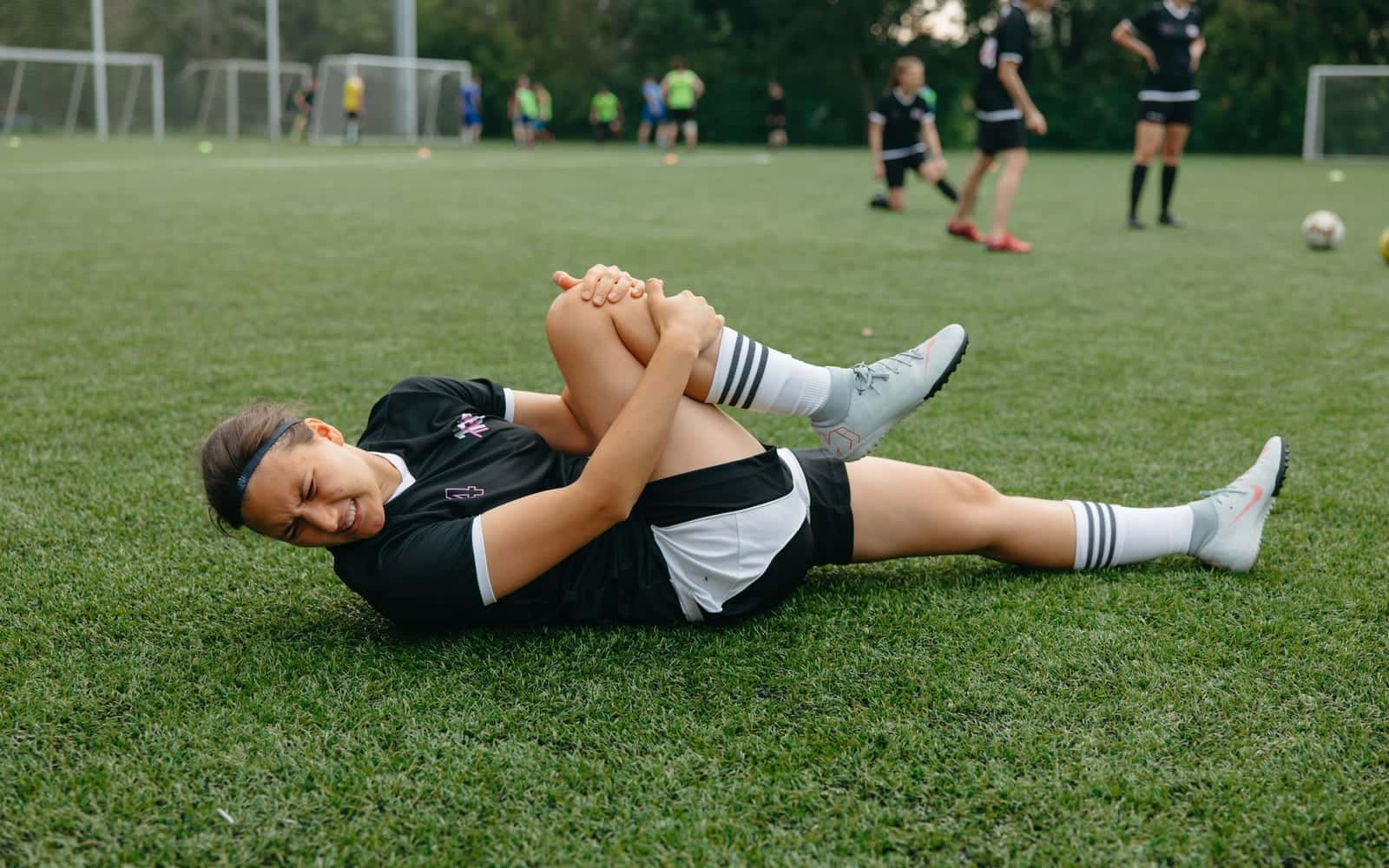 A footballer on the pitch holding an injured knee