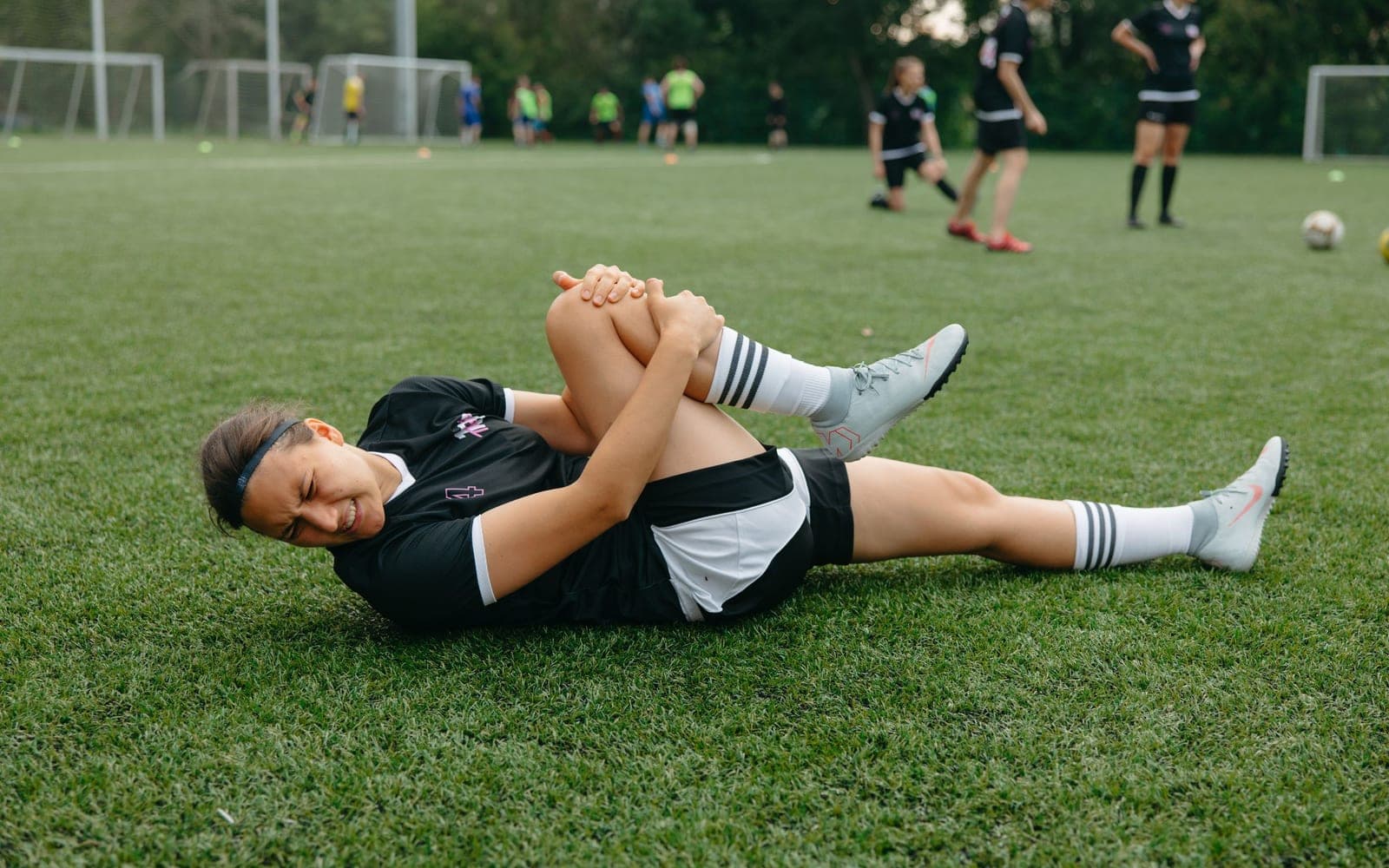 A footballer on the pitch holding an injured knee