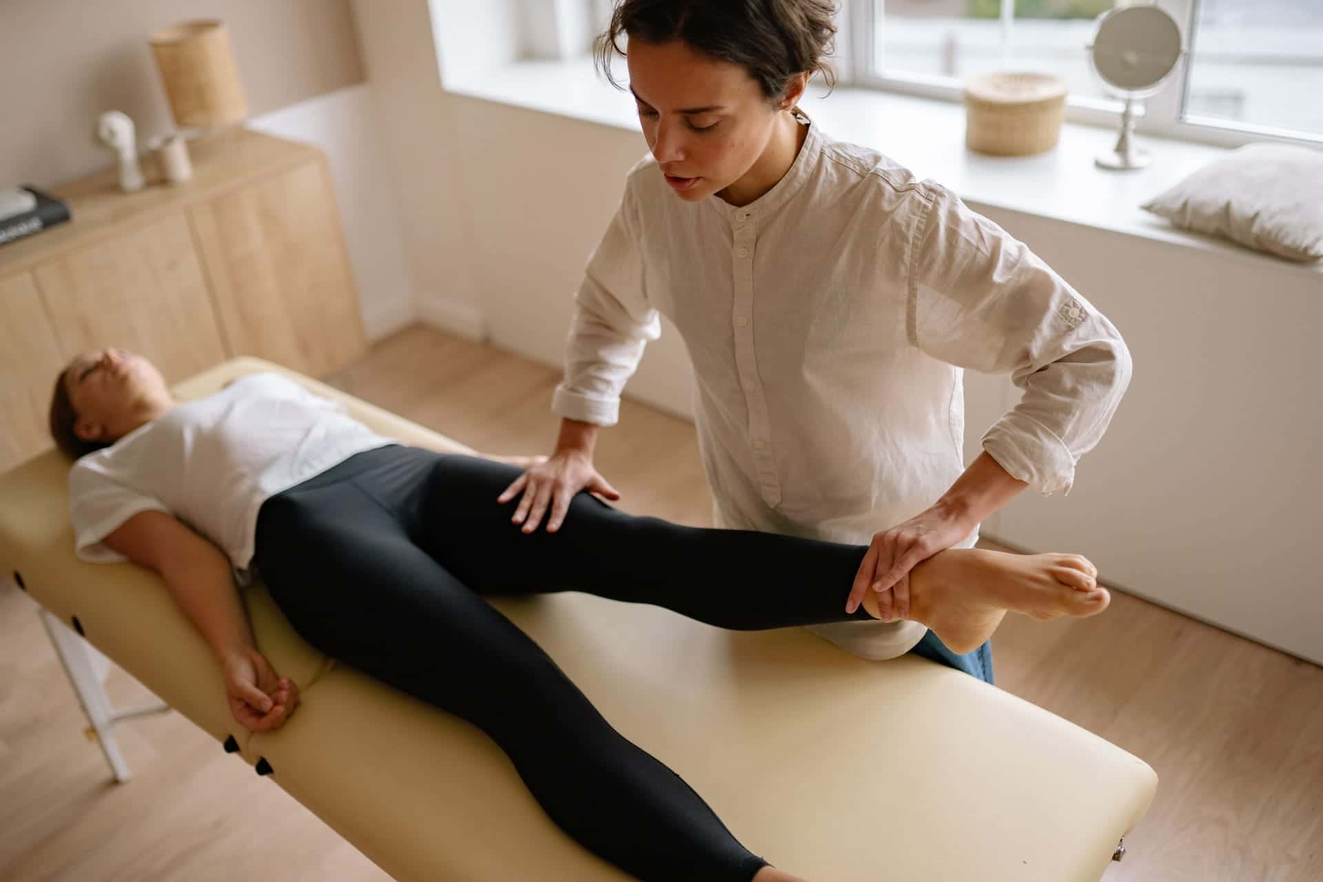 A practitioner assessing a patient's leg on a treatment couch