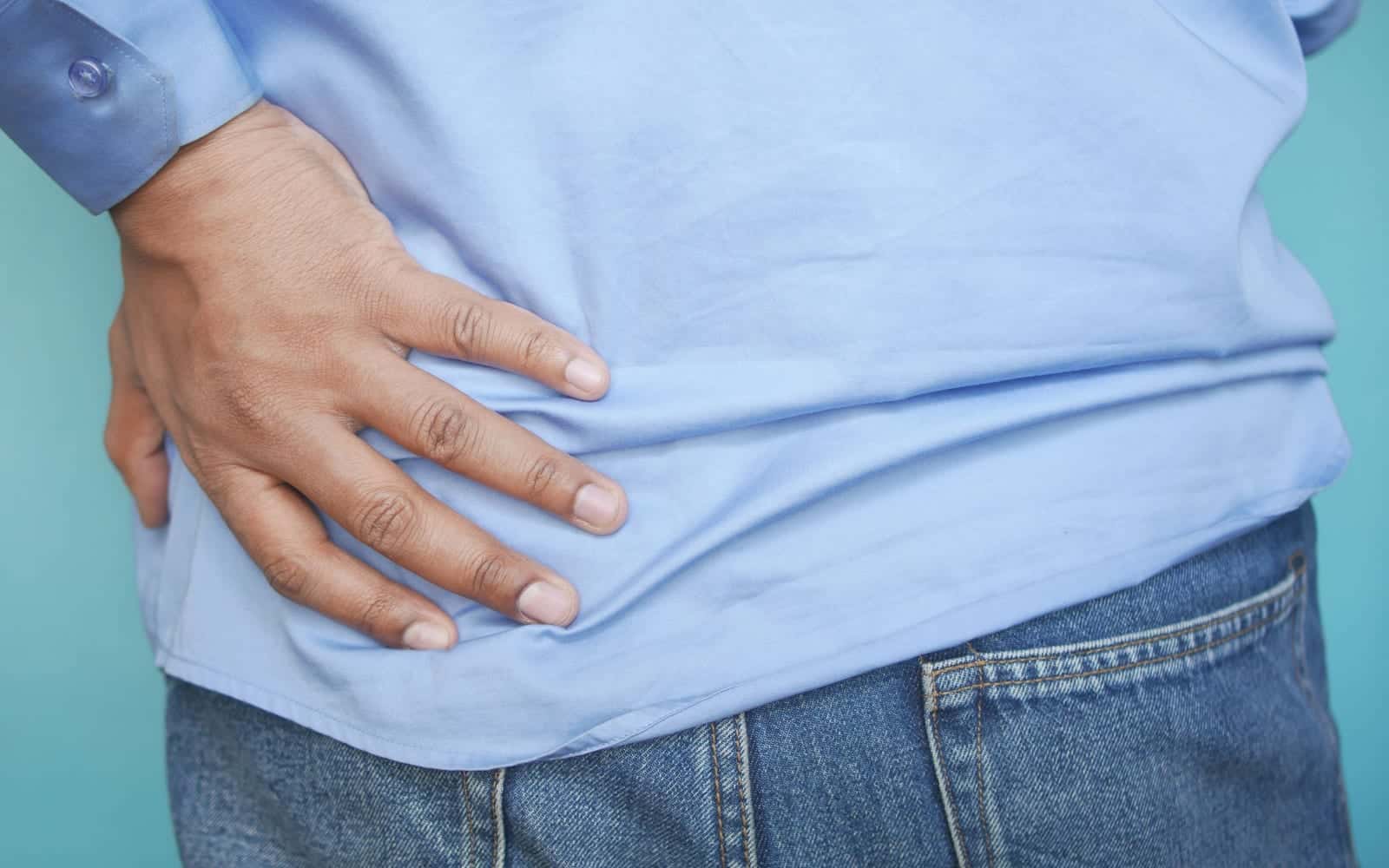 A man in a blue shirt holding his lower back