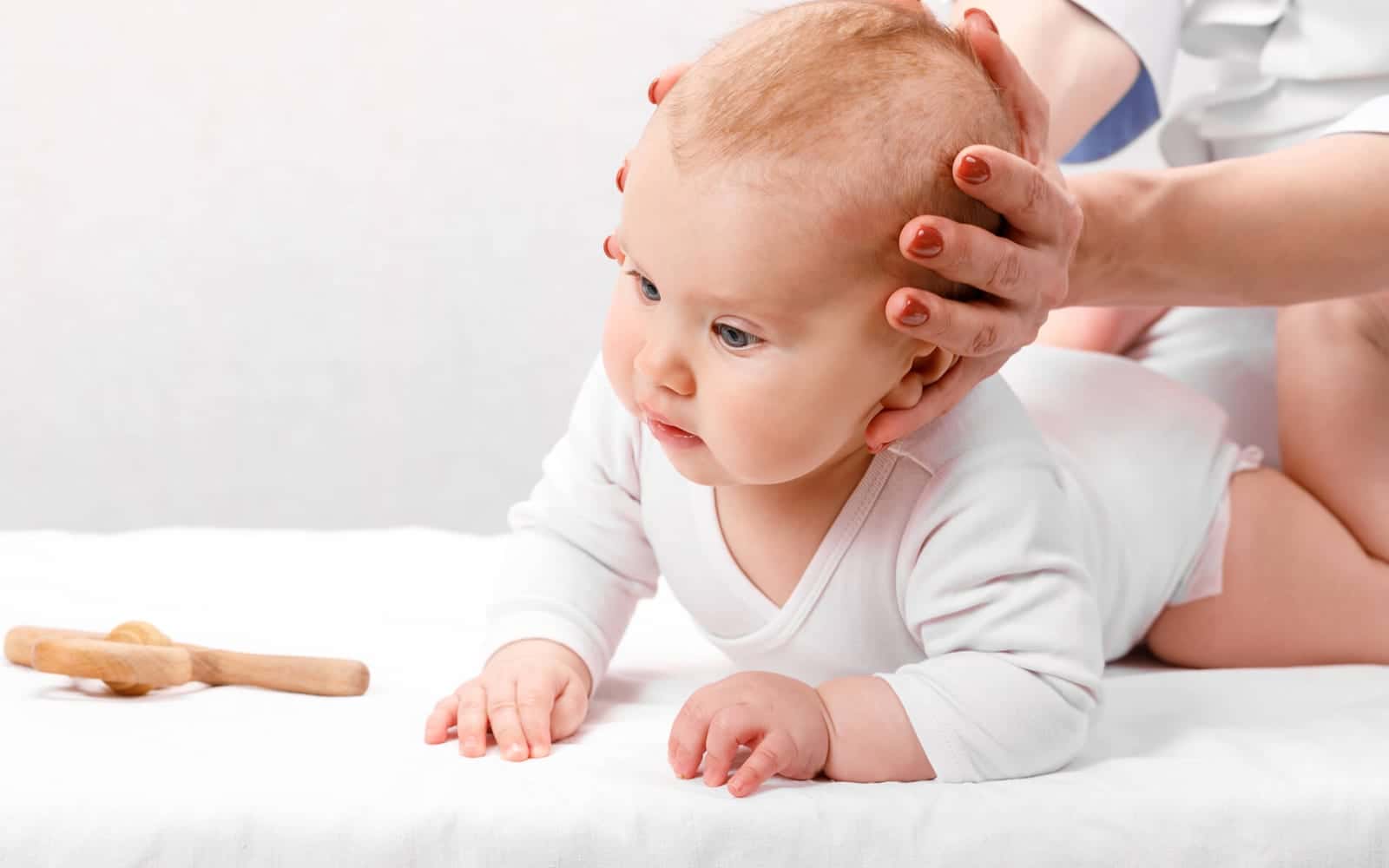 A baby being examined with light touch at the clinic, with a parent alongside