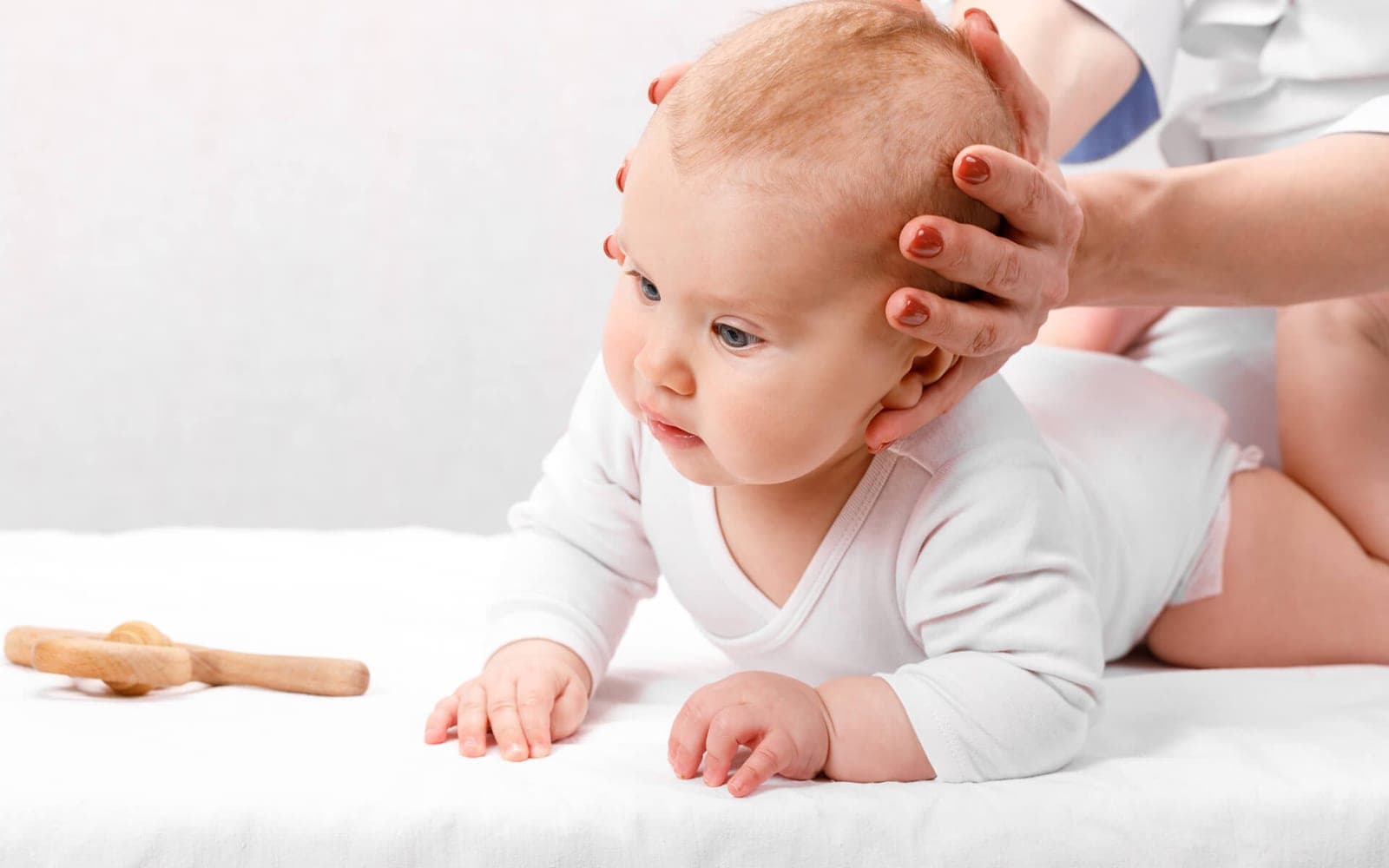 A baby being examined with light touch at the clinic, with a parent alongside