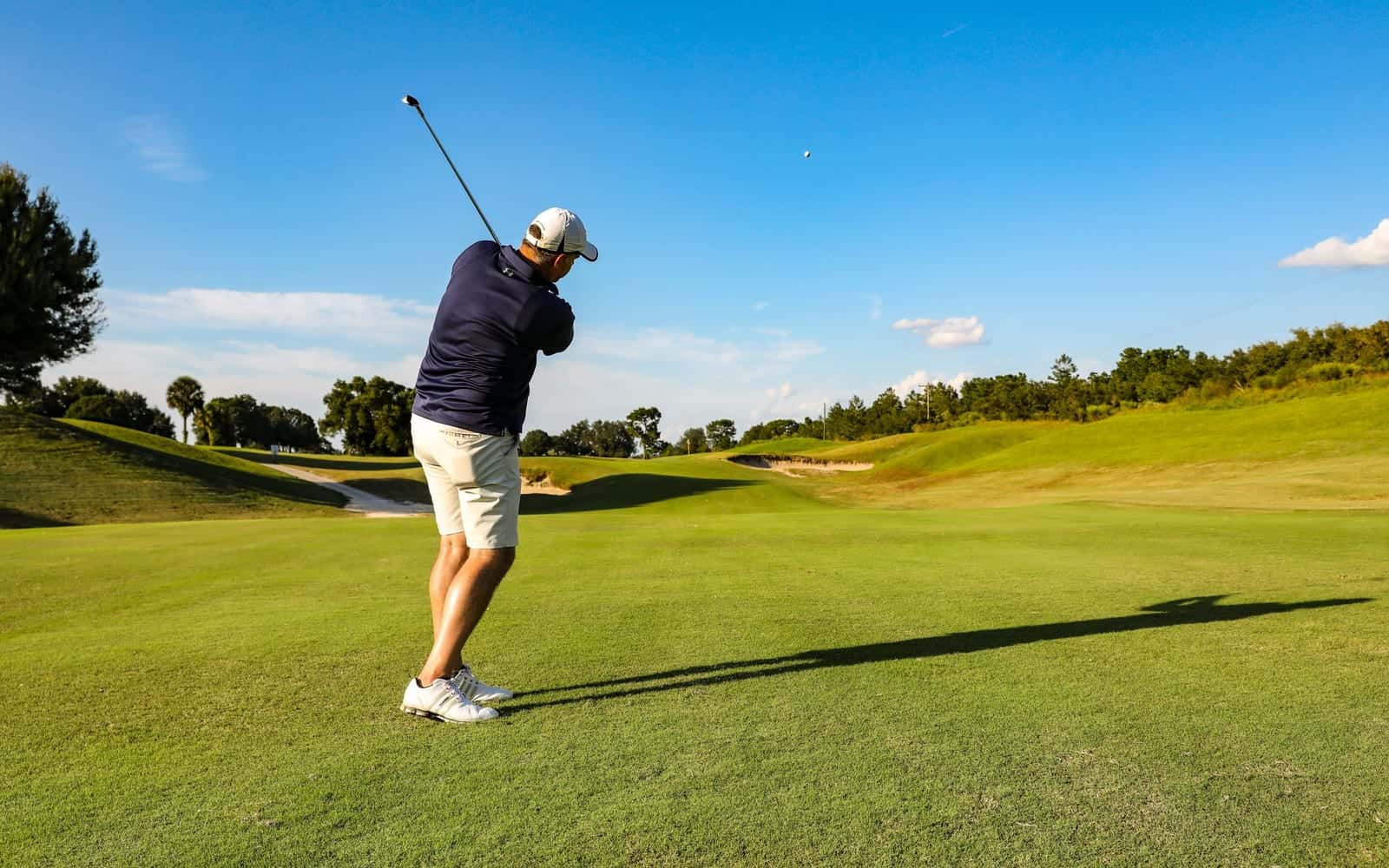 A golfer at the top of his swing on the fairway