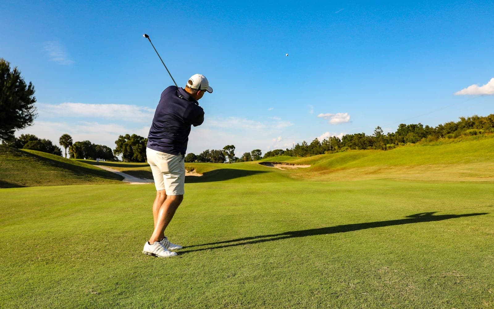 A golfer at the top of his swing on the fairway