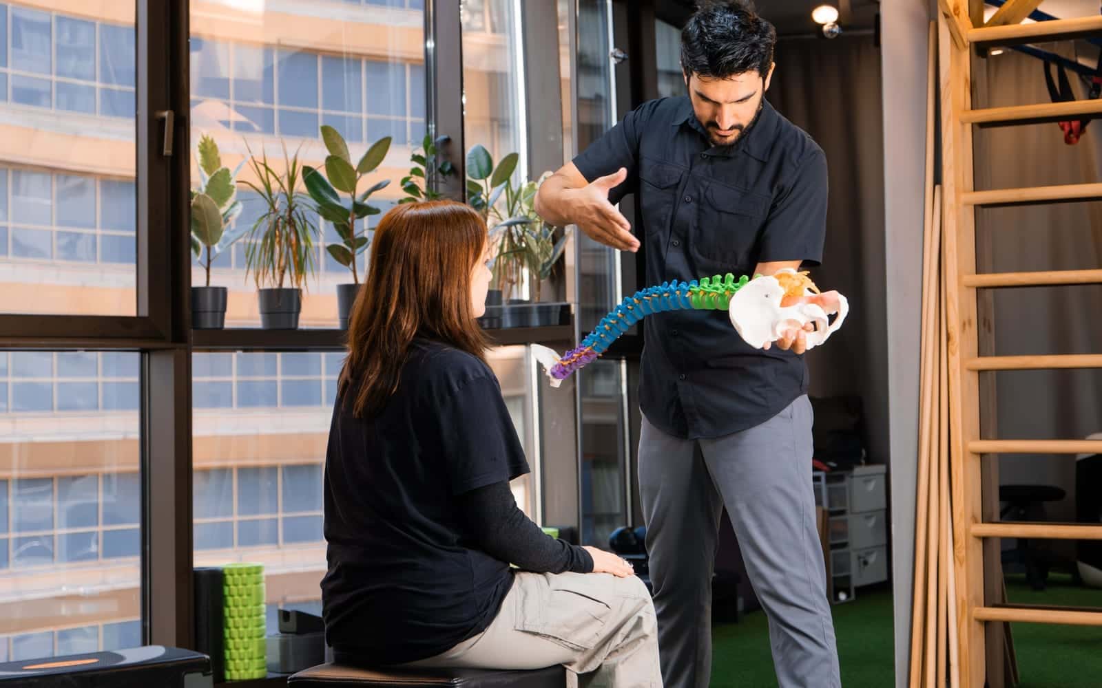 A practitioner explaining a model of the spine to a patient
