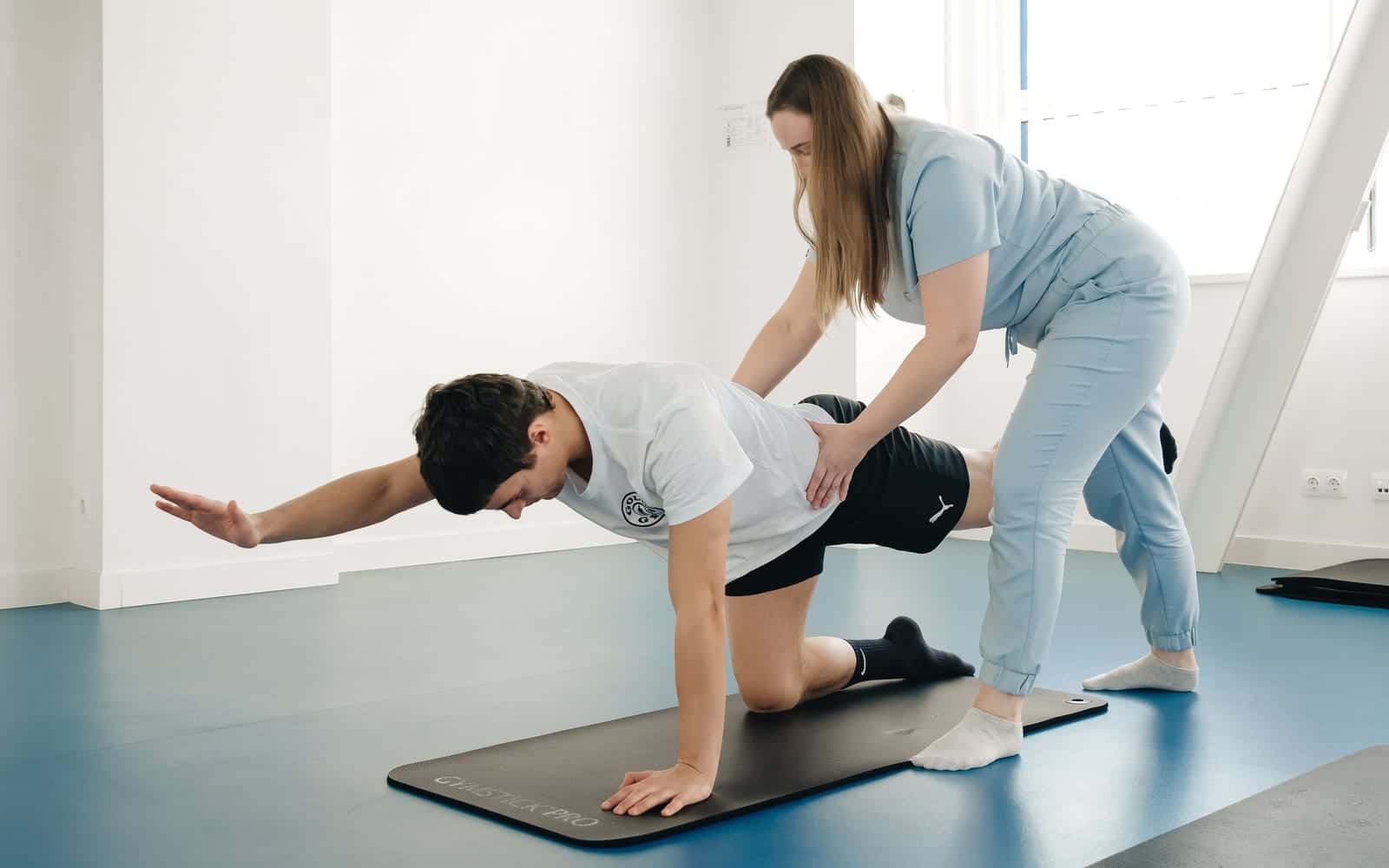 A physiotherapist guiding a patient through a floor exercise