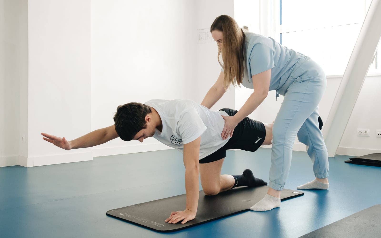 A physiotherapist guiding a patient through a floor exercise