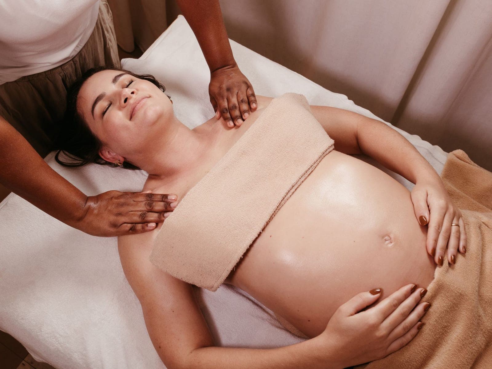 A pregnant woman receiving a gentle shoulder massage on a treatment table