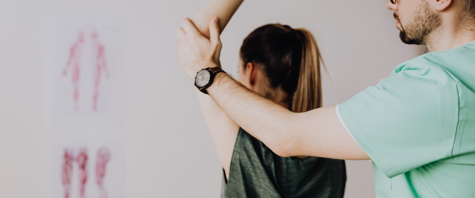 A practitioner assessing a patient's raised arm and shoulder